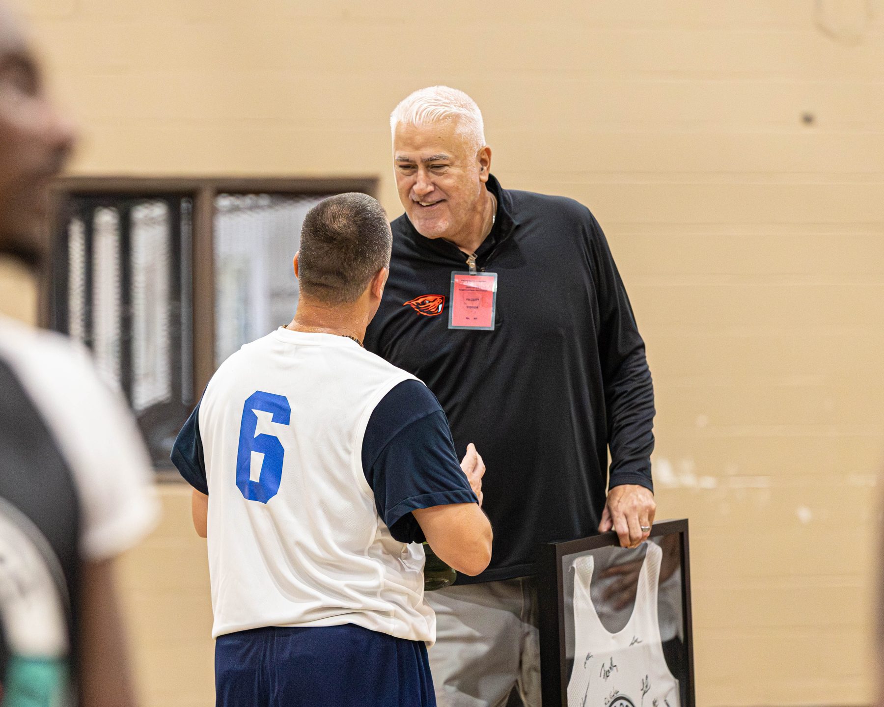 A leader shakes hands with a participant inside a facility gym